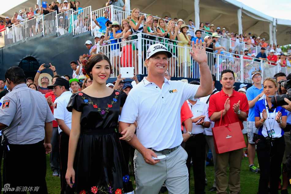 果岭上的家庭庆典:霍夫曼的冠军时刻与深情拥抱 在墨西哥观众热情的包围下,霍夫曼怀抱小女儿,与妻子一同向人群挥手致意,女儿好奇地望向欢呼的观众,场面温馨动人。