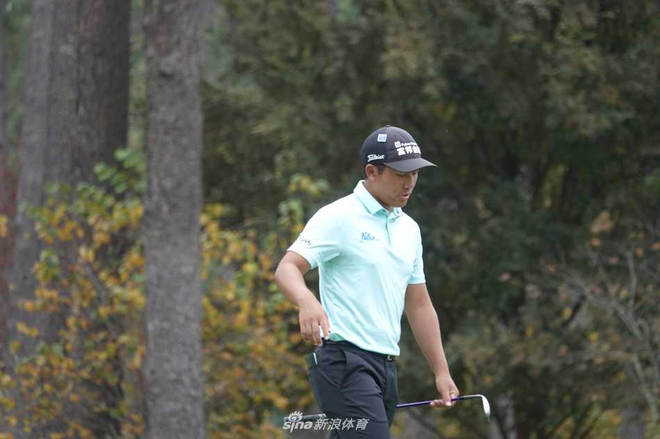 潘政琮与球童在奥古斯塔著名的阿门角附近商讨策略，背景是挑战性极高的球道布局。