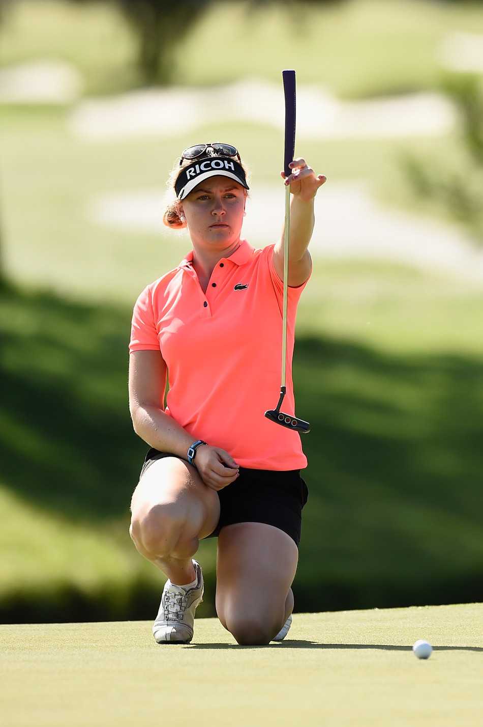 果岭光影间的高尔夫巾帼群像 查莉·霍尔单膝跪地,指尖轻抚果岭,目光如炬地审视着推杆线路上的每一处细微起伏。