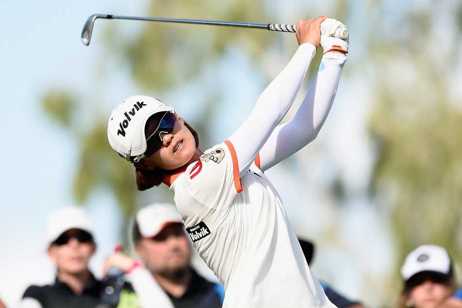 果岭光影间的高尔夫巾帼群像 卡莉·布斯在果岭边屈膝俯身,双眼紧盯小球,正以精妙的力度打出一记至关重要的短杆切击。