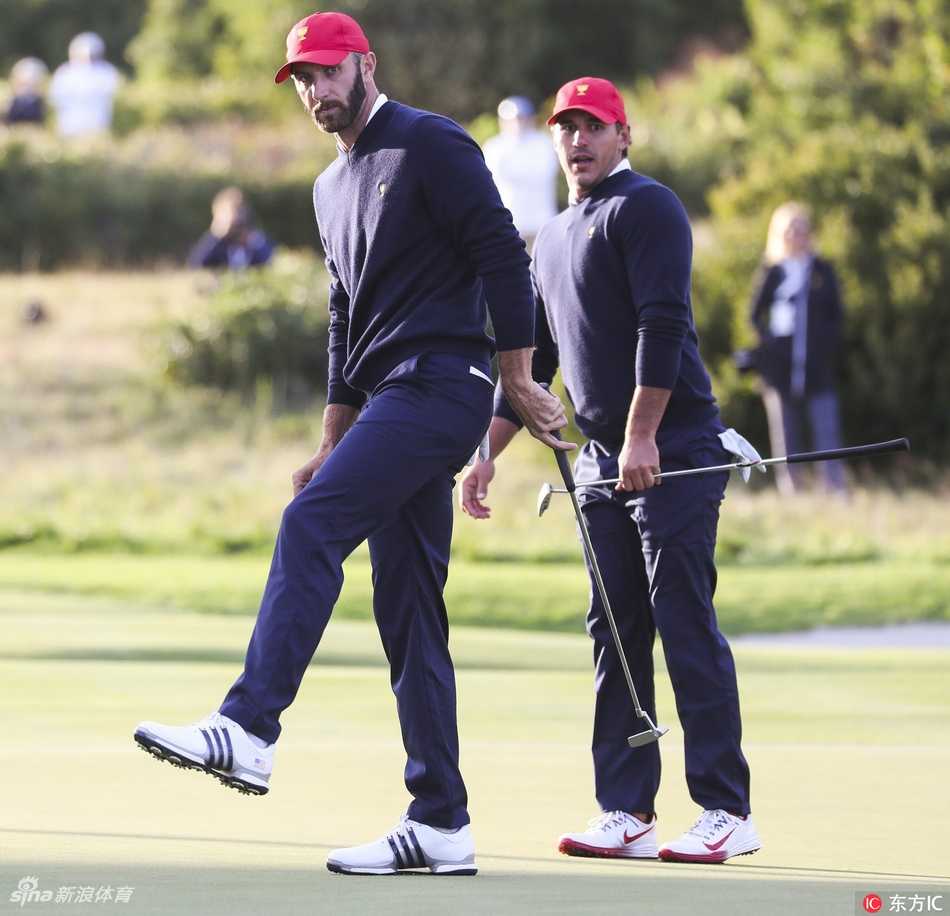 金时沅站立在水塘边的浅水区中，正全神贯注地准备挥杆击打水面下的高尔夫球，水面荡开圈圈涟漪。