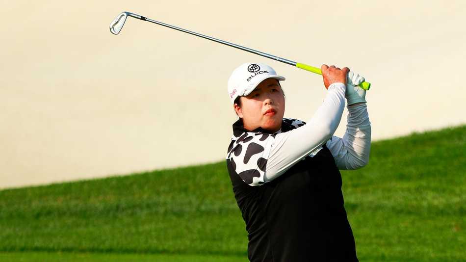 冯珊珊在果岭边凝神观察推杆线路，表情专注而沉着，仿佛正在计算着小白球滚动的每一寸距离。