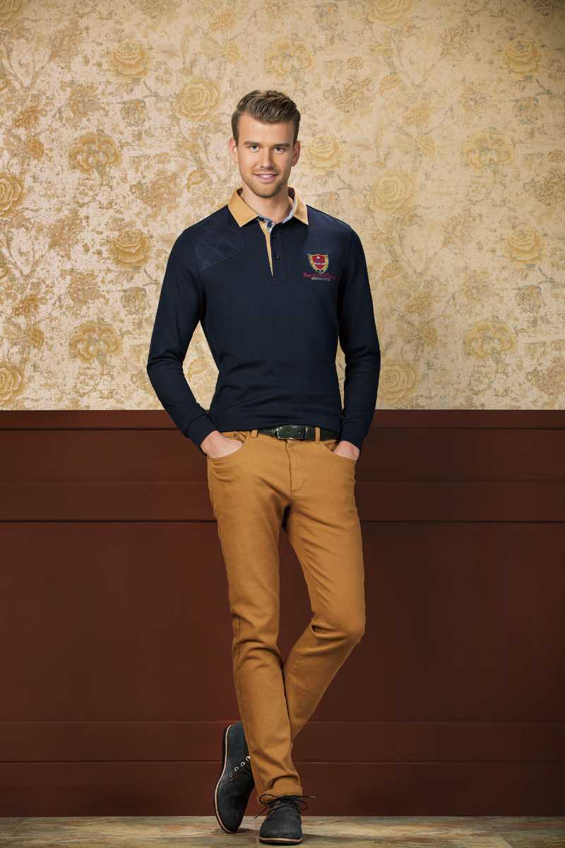 比音勒芬风尚解析:剪裁艺术与色彩交响的时尚哲思 一件色彩对比鲜明的拼色 Polo 衫,湛蓝与纯白在胸前形成大胆分割,模特在绿色草坪背景下显得充满活力与动感。