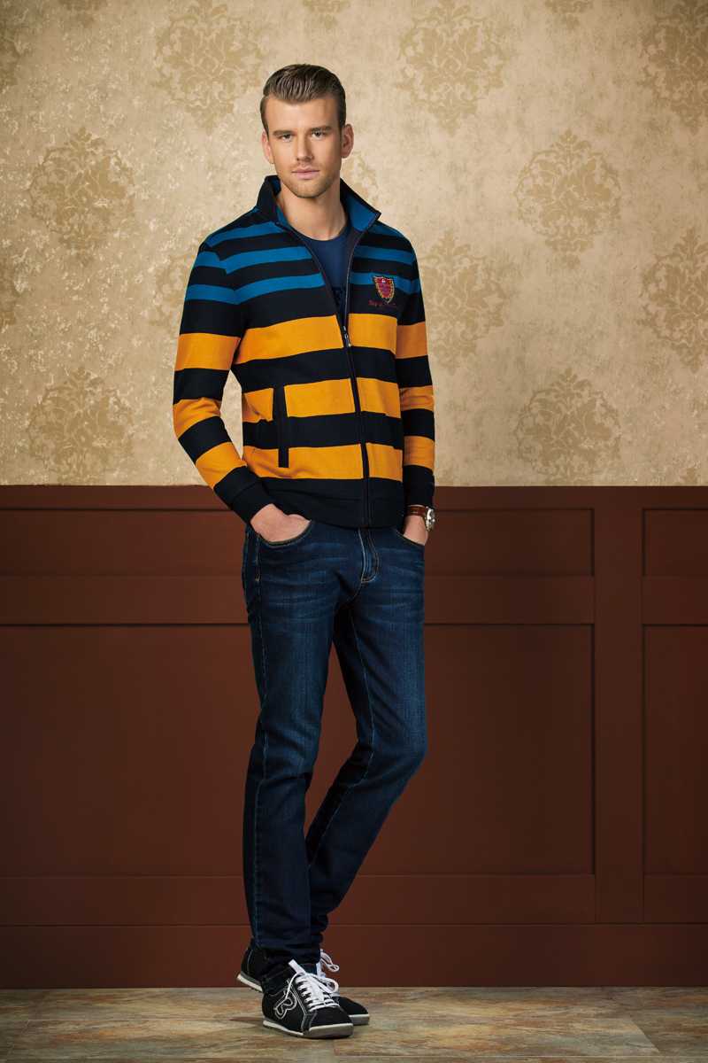 比音勒芬风尚解析:剪裁艺术与色彩交响的时尚哲思 全套都市休闲搭配,模特倚靠复古砖墙,卡其色风衣内搭对比色系毛衣,整体造型色彩和谐又富有层次,尽显秋日儒雅风尚。