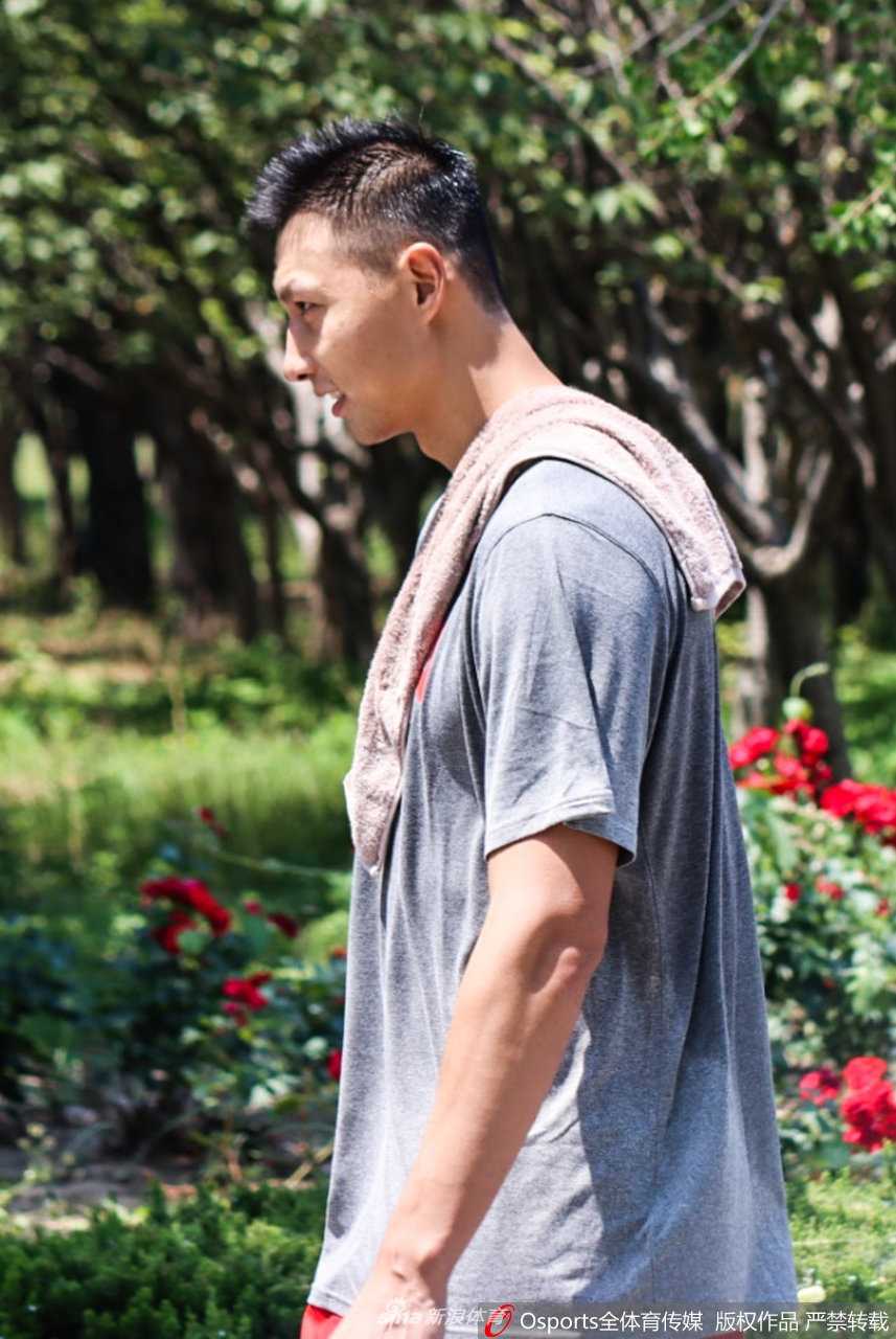 男篮领军者满血归队:易建联回归集训,重塑中国男篮之魂 训练场上,易建联正低头专注地调试手机,身后的背景是空旷的看台。他身着标志性的红色国家队训练背心,肌肉线条依然分明,此刻的平静似乎预示着他在赛场上即将掀起的波澜。