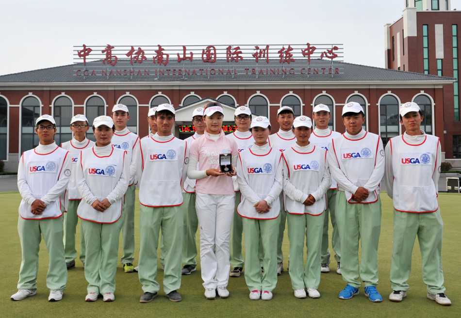 石昱婷闪耀美国女子公开赛的荣耀时刻 石昱婷与她的球童在球道上轻松合影,阳光洒在两人身上,他们手持球杆,笑容真挚,身后是宽阔的果岭,充满了赛后放松的愉悦与团队情谊。