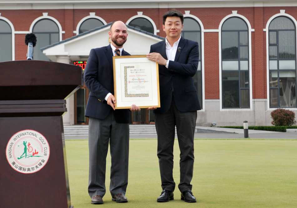 石昱婷闪耀美国女子公开赛的荣耀时刻 USGA官员郑重地将一块精致的感谢牌交予中高协代表手中,双方握手致意,背景板上的赛事标识凸显了这一时刻的官方性与历史意义。