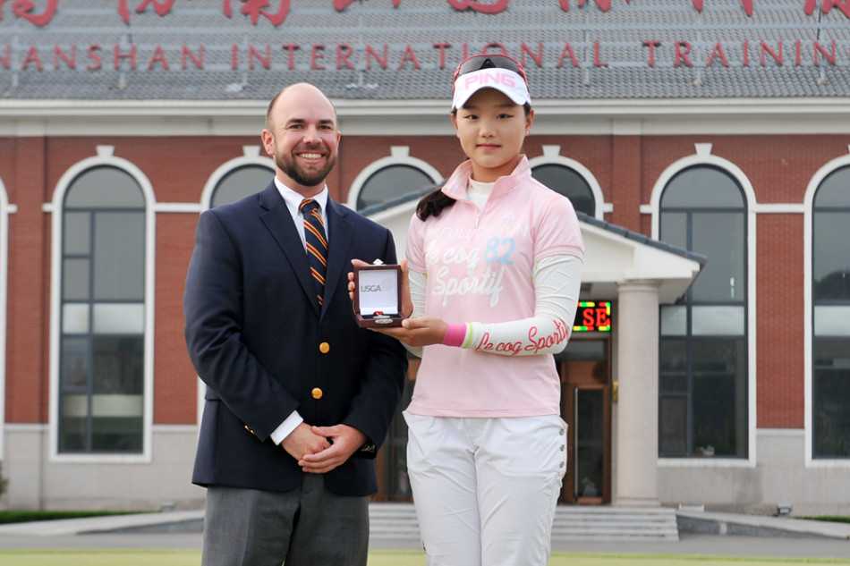 石昱婷闪耀美国女子公开赛的荣耀时刻 石昱婷独自站立,手持奖牌面向镜头露出自信微笑,身后赛场旗帜飘扬,这一刻她光芒四射,尽显冠军风范与青春活力。