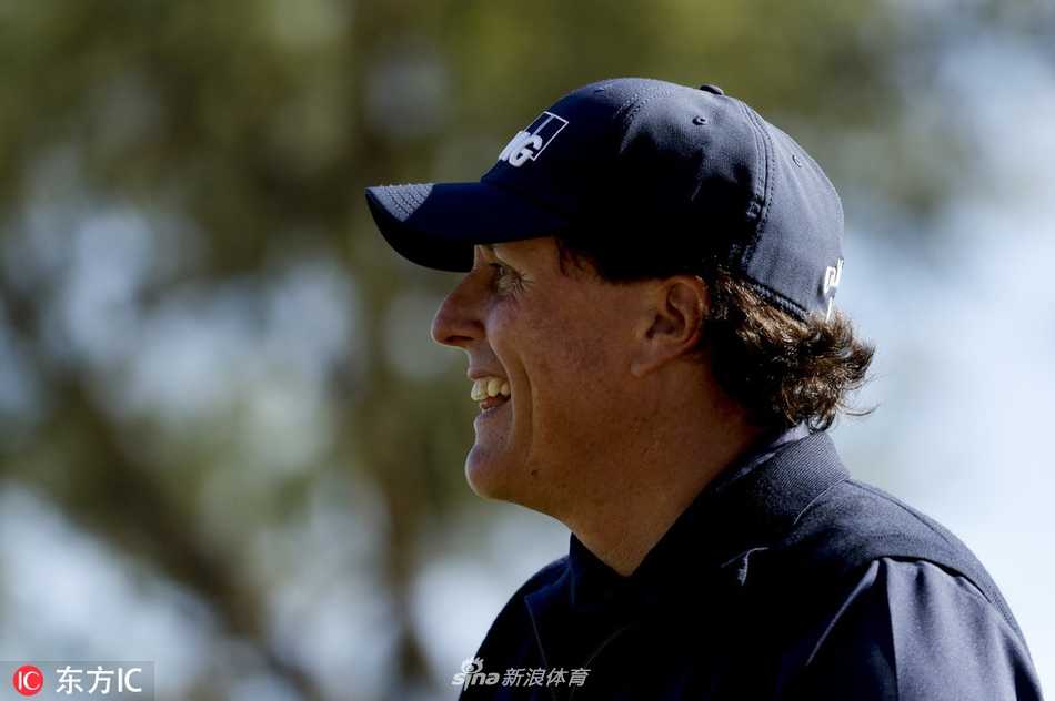 老将米克尔森在果岭边凝神观察推杆线路，眼神专注而坚定，仿佛在计算着风的每一丝变化。