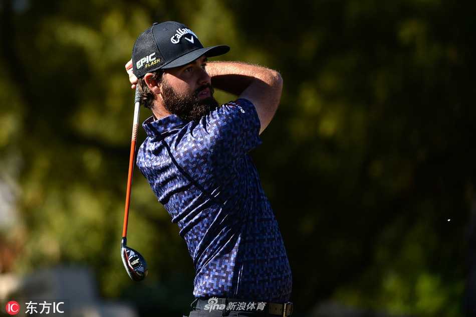 宽阔的球道在棕榈树间延伸，一名球员正在准备开球，展现了沙漠球场独特而恢弘的景观。