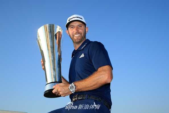 达斯汀·约翰逊在沙坑中救球，他眼神专注，身体紧绷，沙坑杆划起一片细沙，小球精准地飞向洞杯方向。