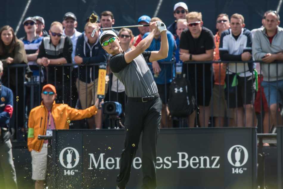 瑞奇·福勒深陷长草区，他双膝微屈，全神贯注地审视球位，手中球杆蓄势待发，准备上演一次关键的长草救球。