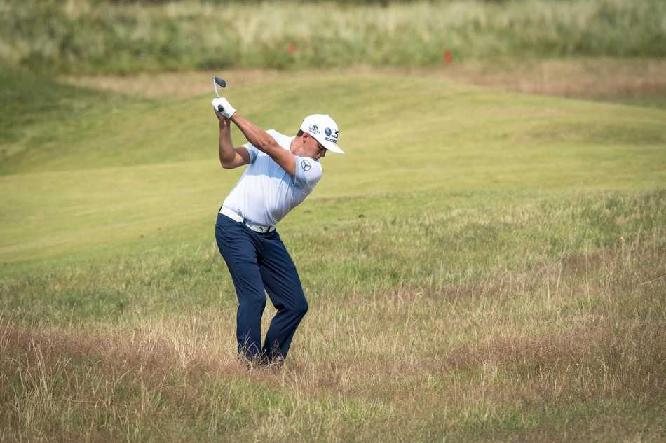 李昊桐在果岭上俯身仔细观察推杆线路，他用手轻抚草皮感受坡度，沉思中计算着力度与转折，决胜尽在方寸之间。