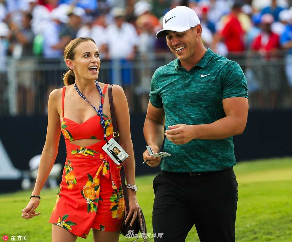 绿茵之外的温情:高尔夫球星们的爱情与家庭故事 里奇·福勒在赛场边专注准备,身旁其漂亮女友正温柔地为他背负球包