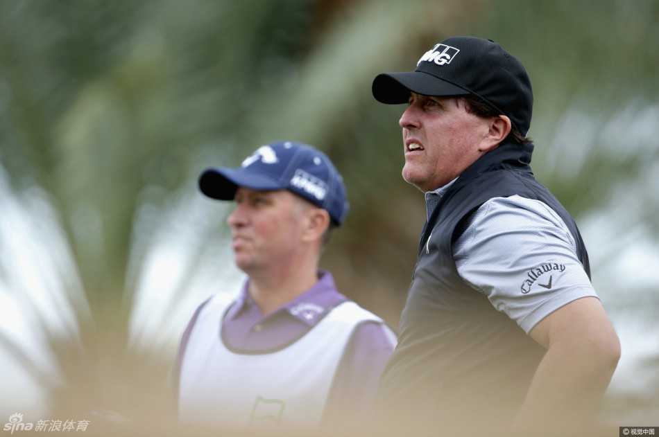 老米与球童‘骨头’马凯在雨中并肩同行，两人正低头密切交谈，共同分析球场状况，是赛场上最可靠的战友。