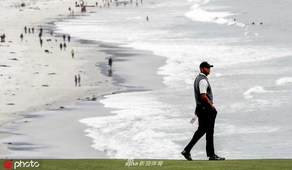 夕阳下，伍兹与同组球员行走在圆石滩球道上，身影被拉长