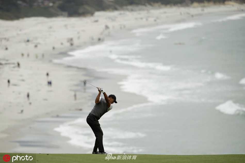 伍兹在第七洞果岭果断推击，小球滚向洞杯瞬间，背景是悬崖与太平洋