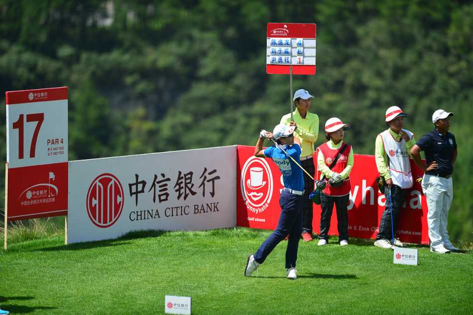 冠军组球员在17号洞果岭凝神推杆，背景是苍翠的山地，比赛气氛紧张而宁静。