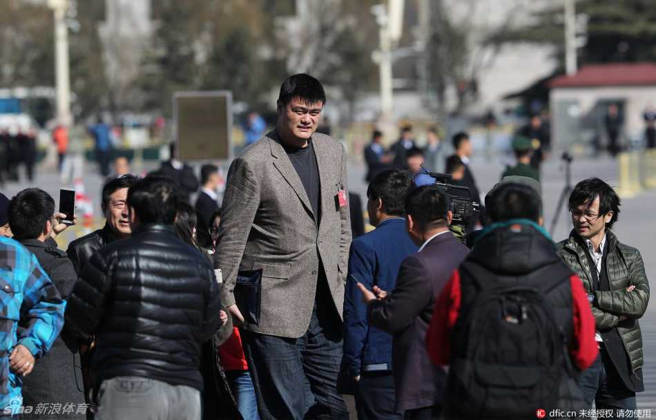 在人群的簇拥下，巨人姚明微微低头，仿佛一座移动的铁塔，从层层包围的记者缝隙中艰难地向大会堂入口移动。