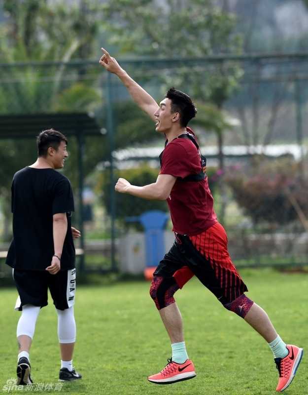 宫鲁鸣指导蹲在场边，手持战术板神情专注地向队员们布置战术，队员们围拢在他身边认真聆听