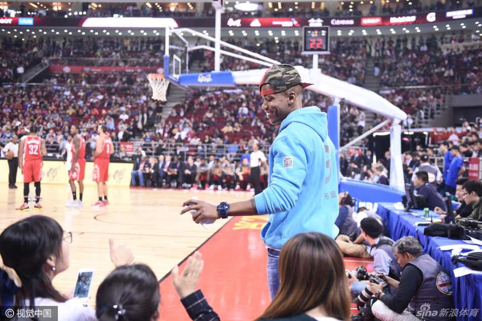 马布里侧身倚靠在座位上，脸上挂着标志性的灿烂笑容，举起手臂向四周认出他的热情球迷挥手示意，仿佛老朋友见面般亲切。