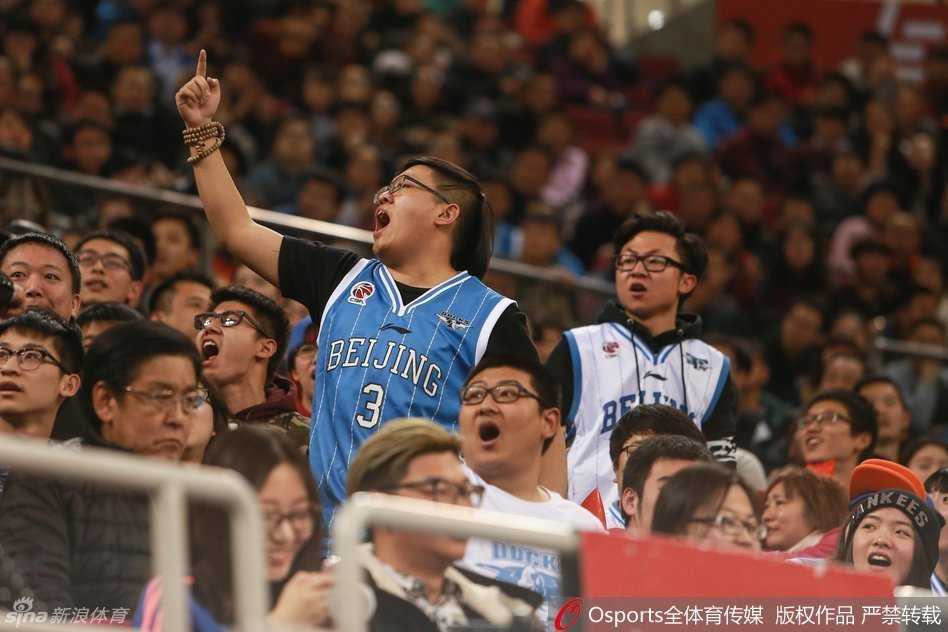 冲突的漩涡中，几名安保人员组成人墙，奋力将一名情绪失控的球迷拦住。该球迷的手臂在空中挥舞，眼神中充满了愤怒与不甘。周围散落的座椅和杂物，无声地诉说着刚刚发生过的激烈对抗。