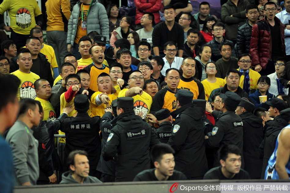 混乱的看台通道内，几名安保人员手挽手形成一道警戒线，努力将情绪激动的球迷隔离开来，为身后的裁判组开辟出一条狭窄而艰难的撤离通道。