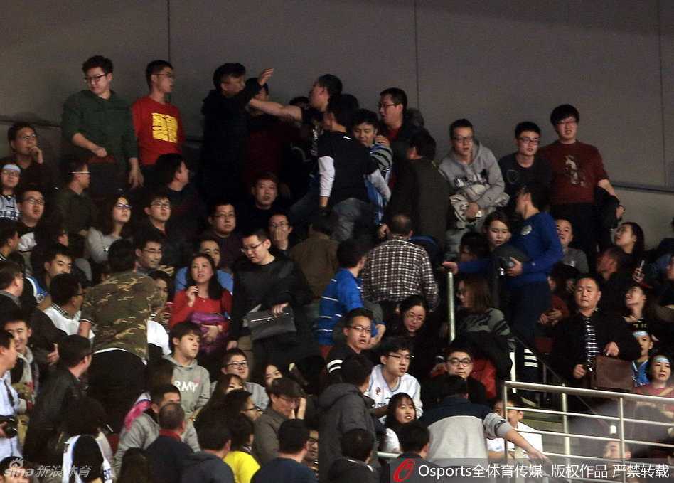 京疆决战夜的五棵松:球迷骚乱与卫冕冠军的悲情谢幕 身穿白色背心的北京球迷情绪失控,探出半个身子越过看台围栏,手臂直指向场地中央,脸上写满了不甘与愤怒,似乎在向场内的工作人员咆哮申诉。