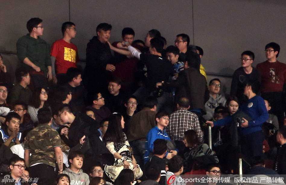 京疆决战夜的五棵松:球迷骚乱与卫冕冠军的悲情谢幕 一名身着灰色安保制服的工作人员在混乱中面容严峻,他张开双臂试图拦住身后汹涌的人群,而在他的前方,是密密麻麻举起手机拍摄现场的围观群众。