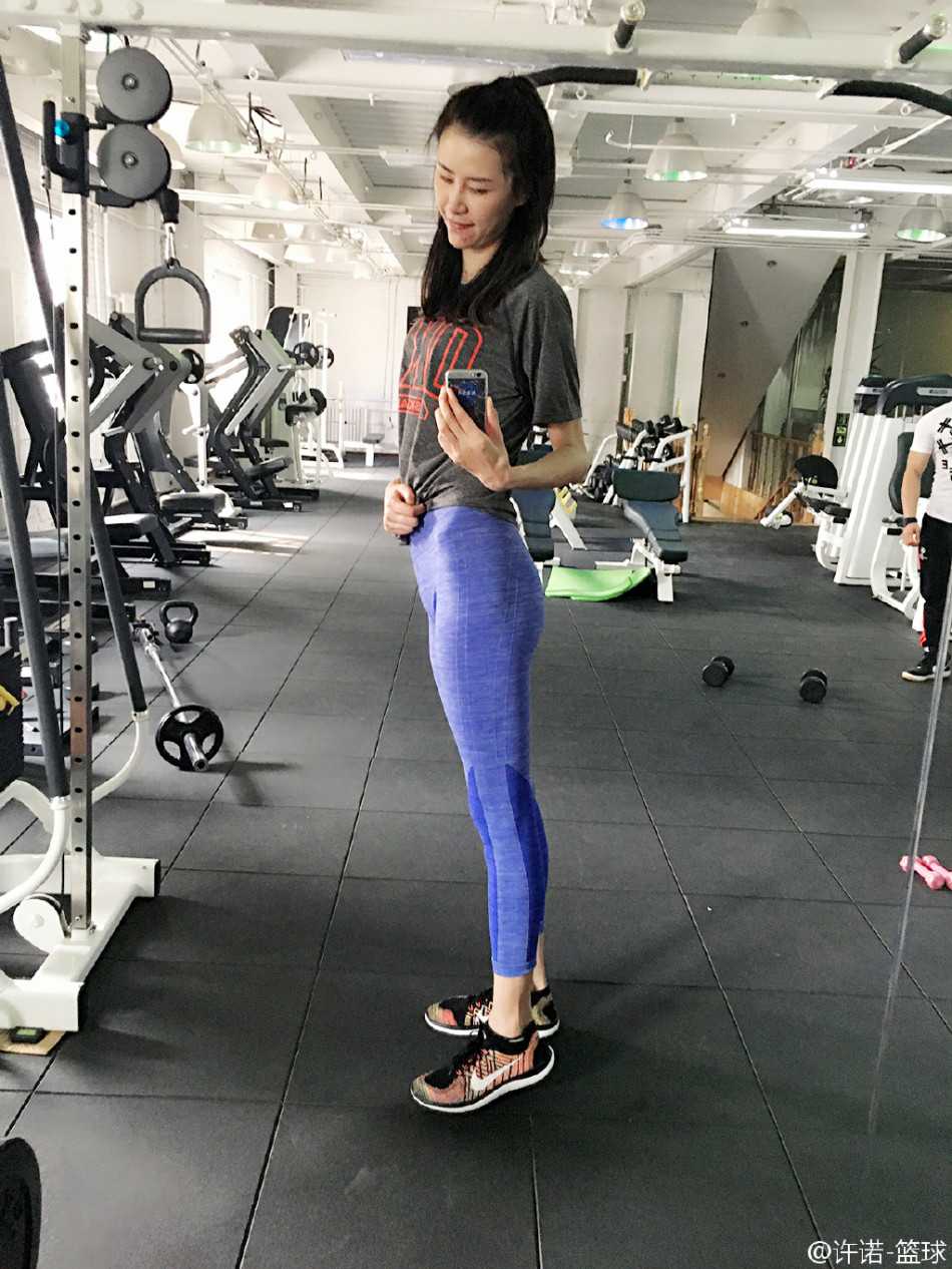 身穿國家隊紅色熱身服的許諾，雙手抱球置於身前，面帶標誌性的甜美微笑，陽光灑在她身上，映照出一位為國爭光的女籃國手的驕傲與榮光。