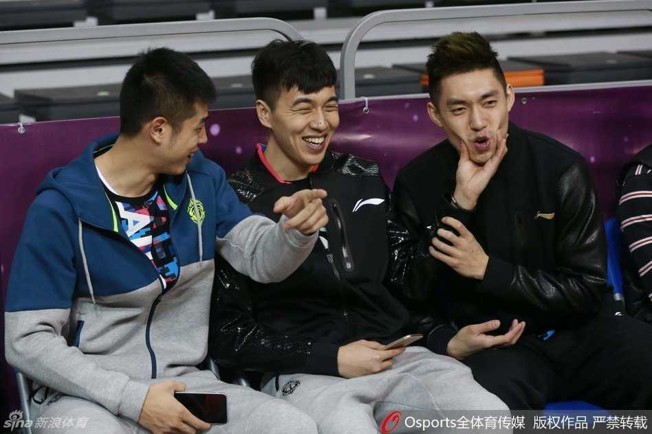 知名解说员于嘉与球星易建联并肩站在场边开心合影，两人面带微笑看向镜头，身后是热闹的赛场和看台上密密麻麻的球迷。