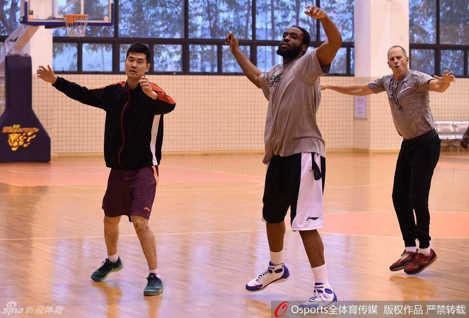 核心易建联正在进行深度的腿部拉伸，面部表情无比专注，紧实的肌肉线条在灯光下熠熠生辉，彰显出顶级运动员的自律与身体状态。