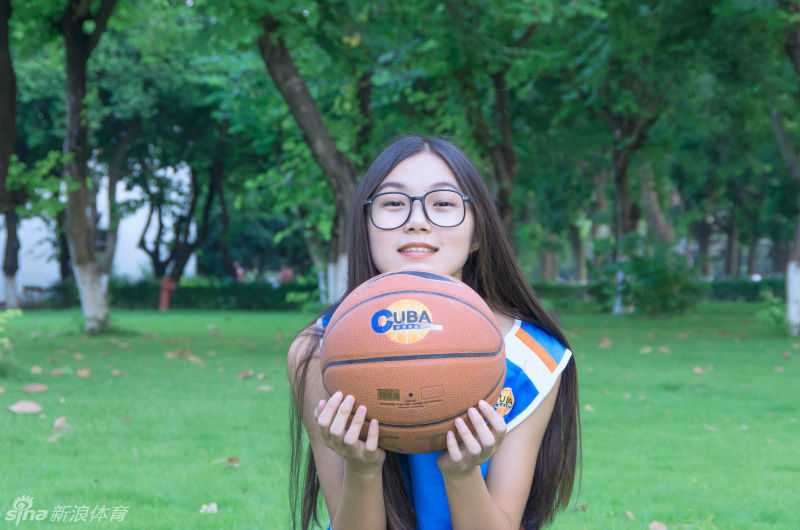 任丹妮双手抱膝坐在球场中央，背景是空旷的看台，宁静的氛围中透露出她对这片挥洒汗水的场地的深深眷恋。