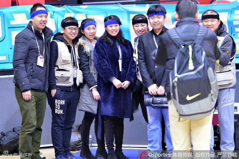 几位记者在媒体工作台上整理采访设备，他们头上的发带与桌上的电脑、秩序册形成鲜明对比，这条小小的布带承载了比比赛本身更复杂的情绪。