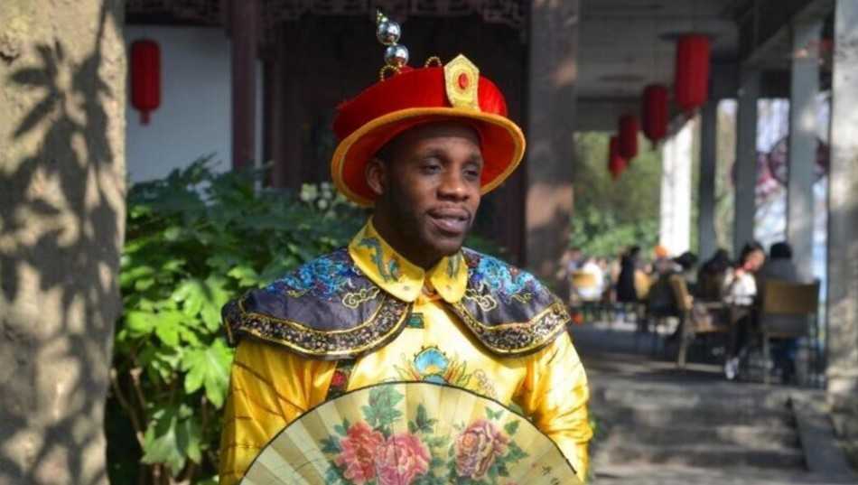 哈德森龙袍加身全家福 辽篮之神中国年味浓 哈德森身穿金色龙袍气宇轩昂,怀抱小女儿尽显铁汉柔情,身旁的大女儿乖巧可爱,一家人在影楼的中式布景前留下珍贵合影