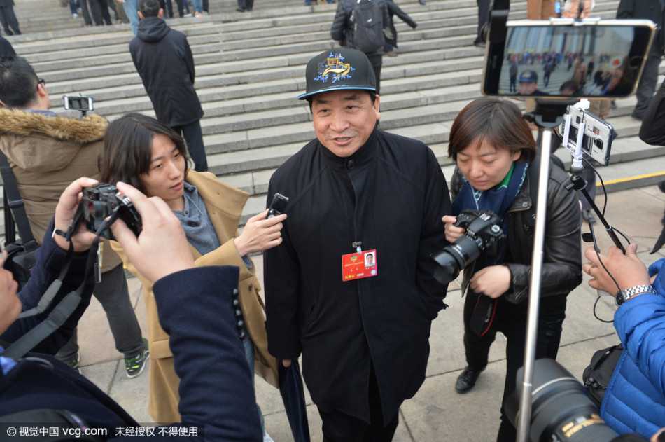 春日的阳光洒在人民大会堂台阶上，姜昆面带标志性的微笑，头顶蓝色北京冠军帽信步走来，眼神中透出履职的从容与自信。