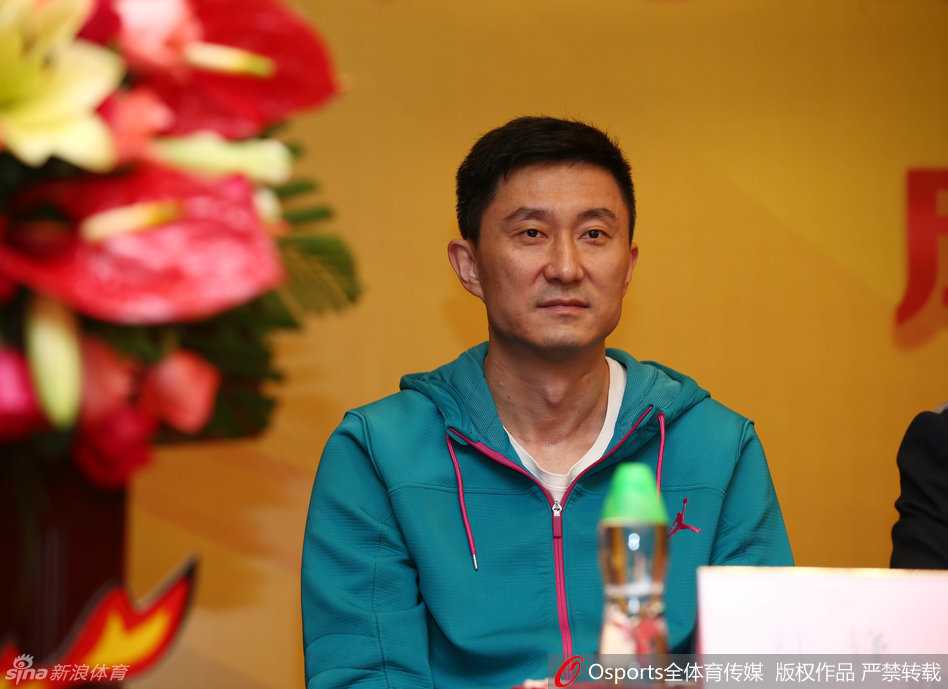 宏远拓土新蓝图,锋雨助阵青训营——广东宏远体育培训扬帆起航 宏远酒店宴会厅内,杜锋身着深色西装,双手插袋侧身倾听,眼神专注地投向发言席,背景板上的公司名称格外醒目,现场气氛庄重而热烈。