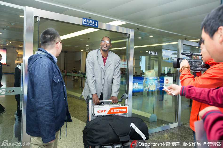 罗德俯身趴在隔离栏上，手持签字笔为一名小球迷在篮球上签名，周围的球迷纷纷举起手机记录下这温情的一刻，罗德的眼中满是宠爱。