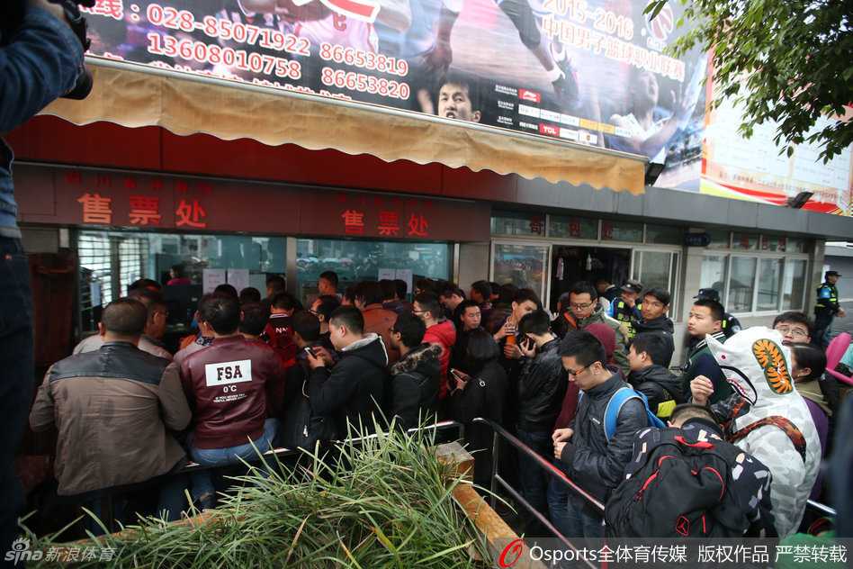 画面中可见购票长龙一眼望不到头，球迷们自备的各种小板凳和瑜伽垫在队伍旁一字排开，大家一边聊天一边耐心等待着清晨的开票时刻。