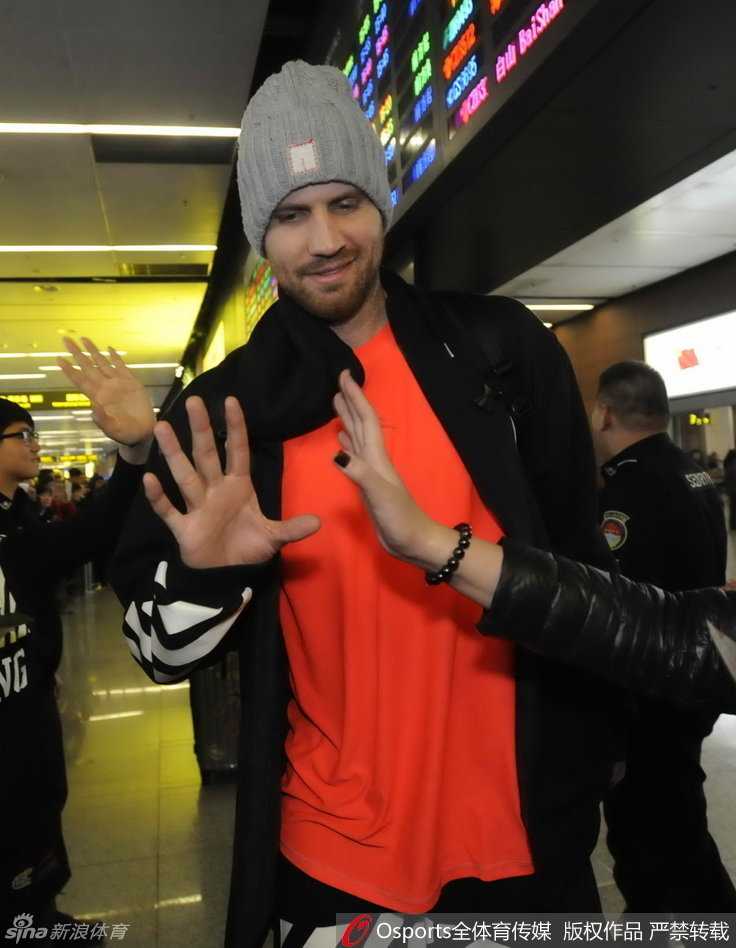 队长杨鸣被球迷团团围住，他耐心地停下脚步，微低着头为身边的球迷签名，周围球迷的脸上洋溢着幸福的笑容，纷纷用手机记录下这难得的近距离接触时刻。