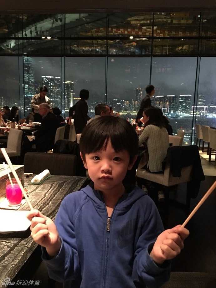 父子三人并排而坐，全神贯注地盯着电视屏幕看动画片，相似的姿势和神情透露出他们之间深厚的默契与亲情。