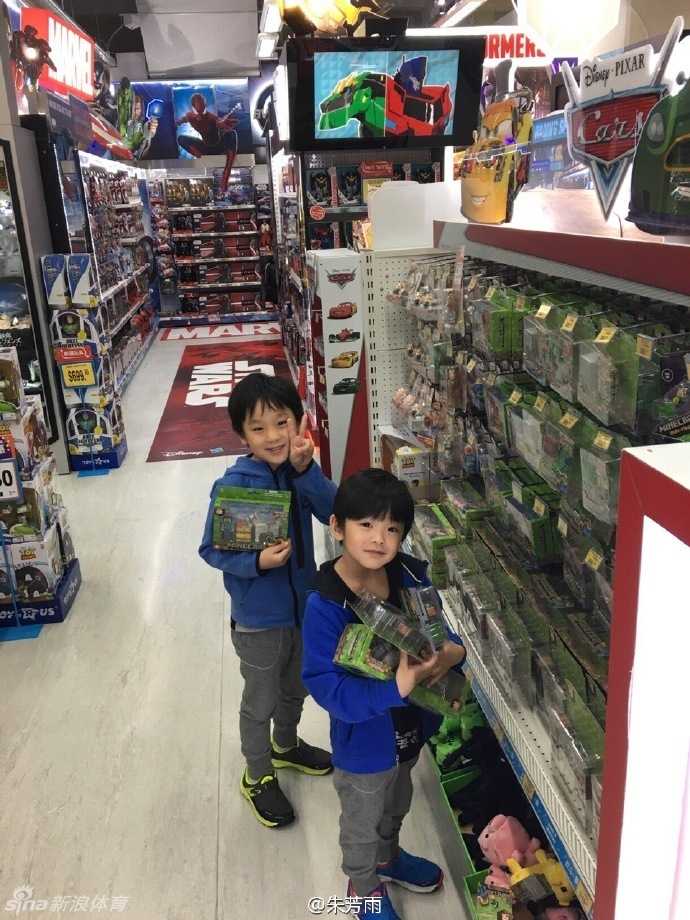 两个小家伙兴奋地摆弄着新到手的玩具，其中一位还调皮地对着镜头咧嘴大笑，天真烂漫的模样十分惹人喜爱。