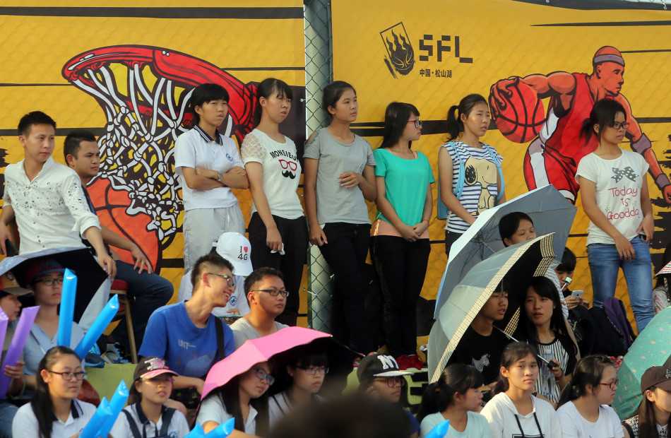 场边的观众席座无虚席，几位美女球迷也被激烈的比赛吸引，目不转睛地关注着场上局势。