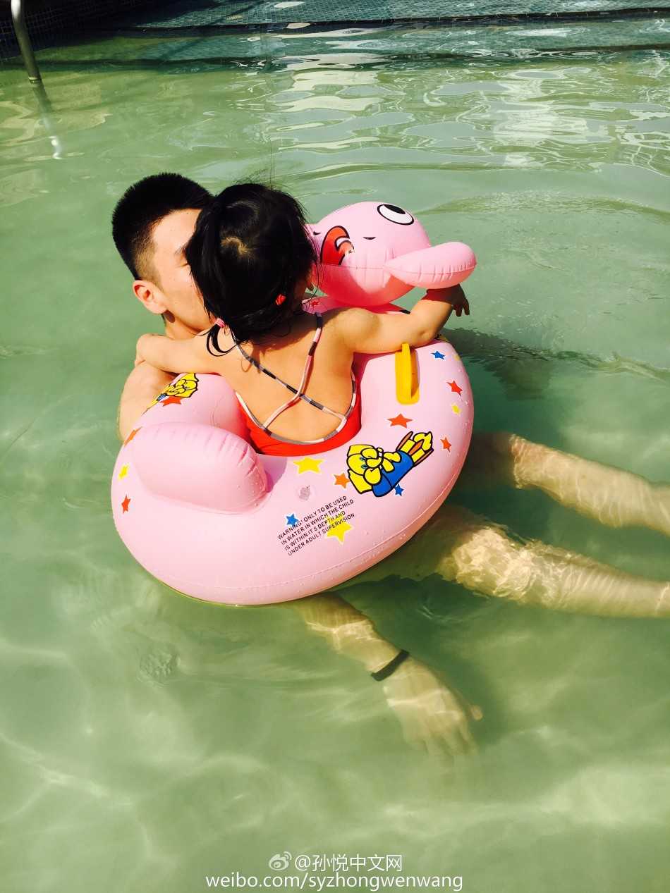 小月亮独自坐在卡通游泳圈中漂浮在水面，孙悦在不远处微笑守护，画面宁静温馨
