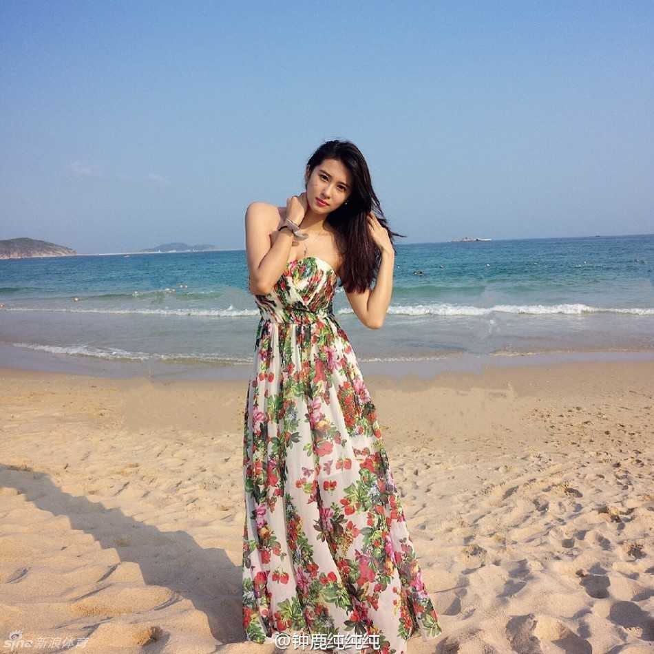 钟鹿纯身着清凉装束站在海边，回眸一笑，飘逸的发丝在阳光下闪着金光，仿佛海风都为之驻足。