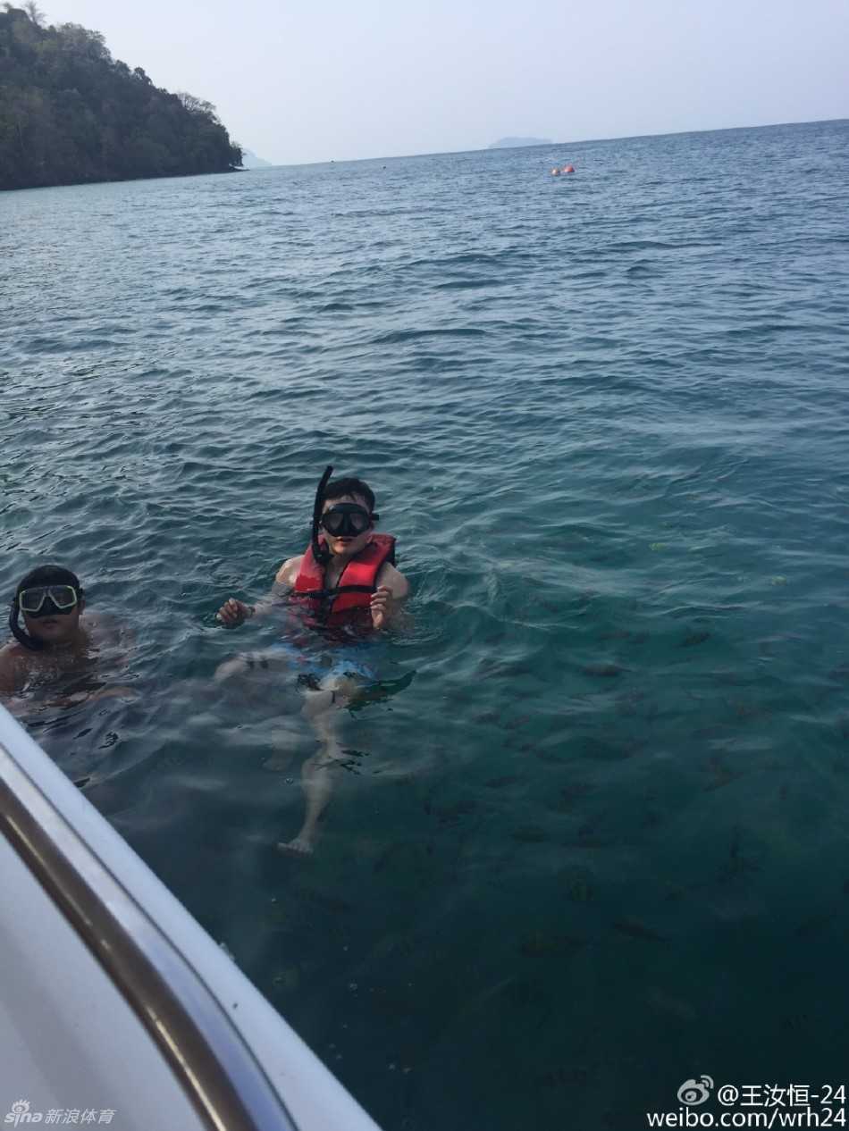 王汝恒身穿潜水服浮在海面，对着镜头比出胜利手势，蔚蓝海水映衬着他的好心情