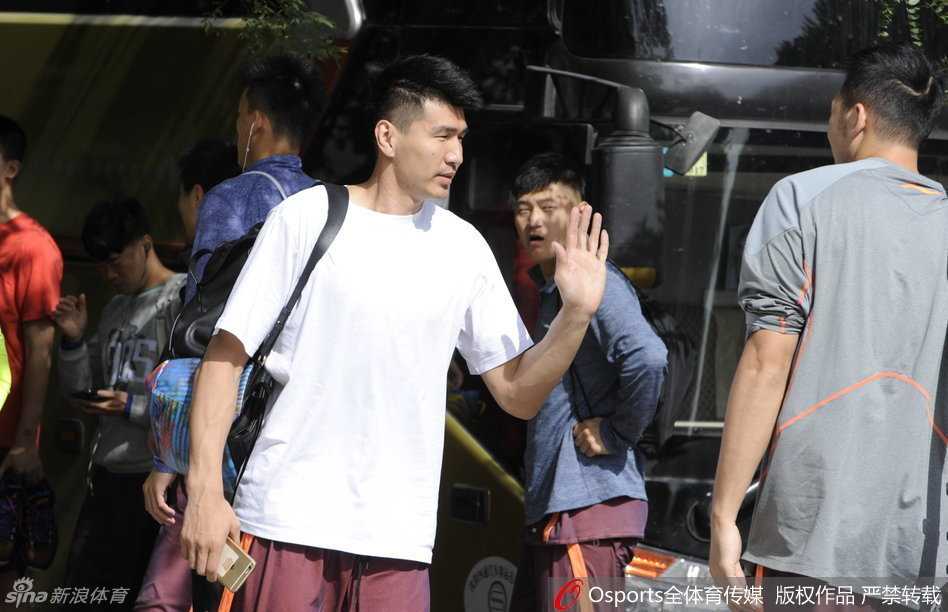 山西男篮主帅许晋哲手拿战术板，身体微微前倾，正在为围拢成一圈的队员们详细讲解战术跑位，眼神中透着学院派教练特有的严谨与睿智。