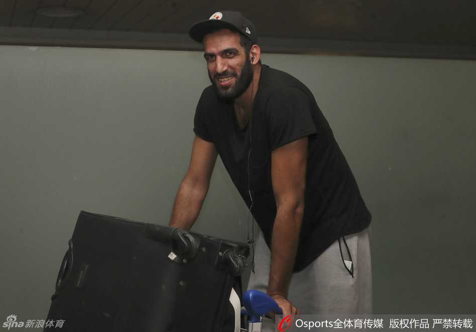 哈达迪在机场与热情的四川球迷互动，他面带笑容侧耳倾听球迷的问候，身后的落地窗外是成都的天空，画面里流淌着跨越国界的真挚情感。