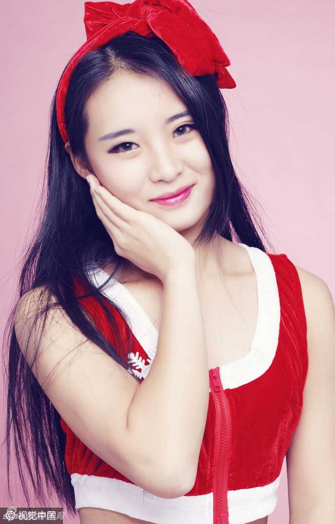 镜头拉近，这位啦啦队员的五官显得尤为精致。她头戴红色圣诞帽，手捧小巧的圣诞树装饰，眼神温柔而明亮，甜美笑容中蕴含着历经风波后的从容与坚定。