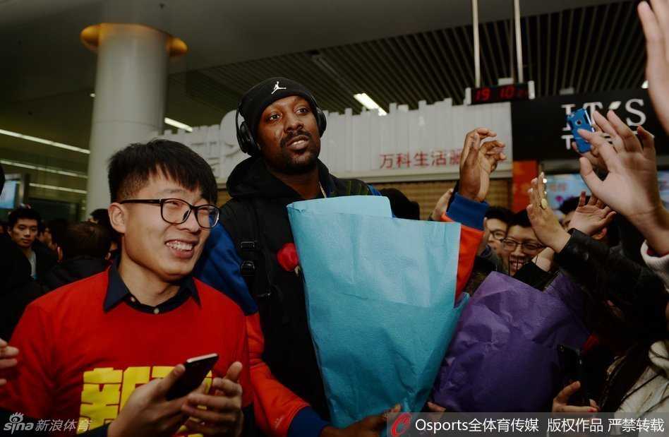 外援布莱切被热情的新疆球迷团团围住，他笑容满面地低头为一名男球迷签名，周围人墙层层叠叠，气氛热烈。